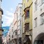 Menschen gehen auf einer gepflasterten Straße mit bunten historischen Gebäuden